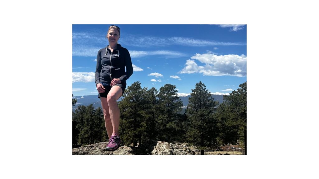 Stacey standing on a rock in the mountains of Colorado after recovering from her TMS Journey.